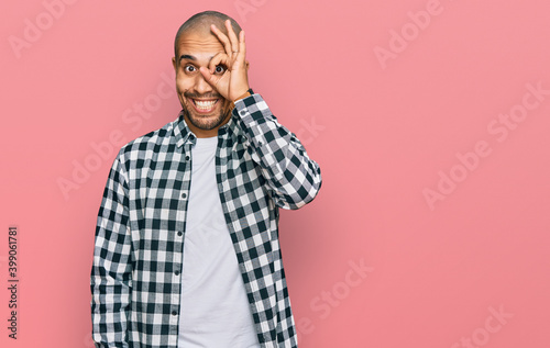 Hispanic adult man wearing casual clothes doing ok gesture with hand smiling, eye looking through fingers with happy face. © Krakenimages.com