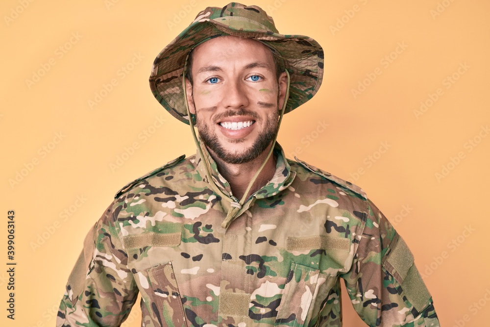 Young caucasian man wearing camouflage army uniform with a happy and cool smile on face. lucky person. Young caucasian man wearing camouflage army uniform with a happy and cool smile on face. lucky person.
