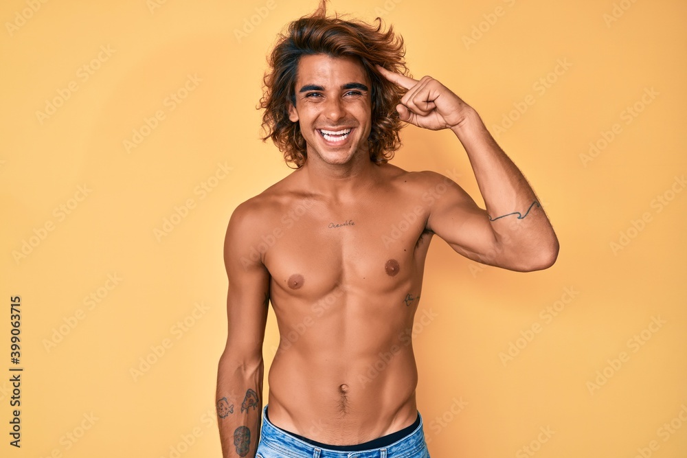 Young hispanic man standing shirtless smiling pointing to head with one finger, great idea or thought, good memory