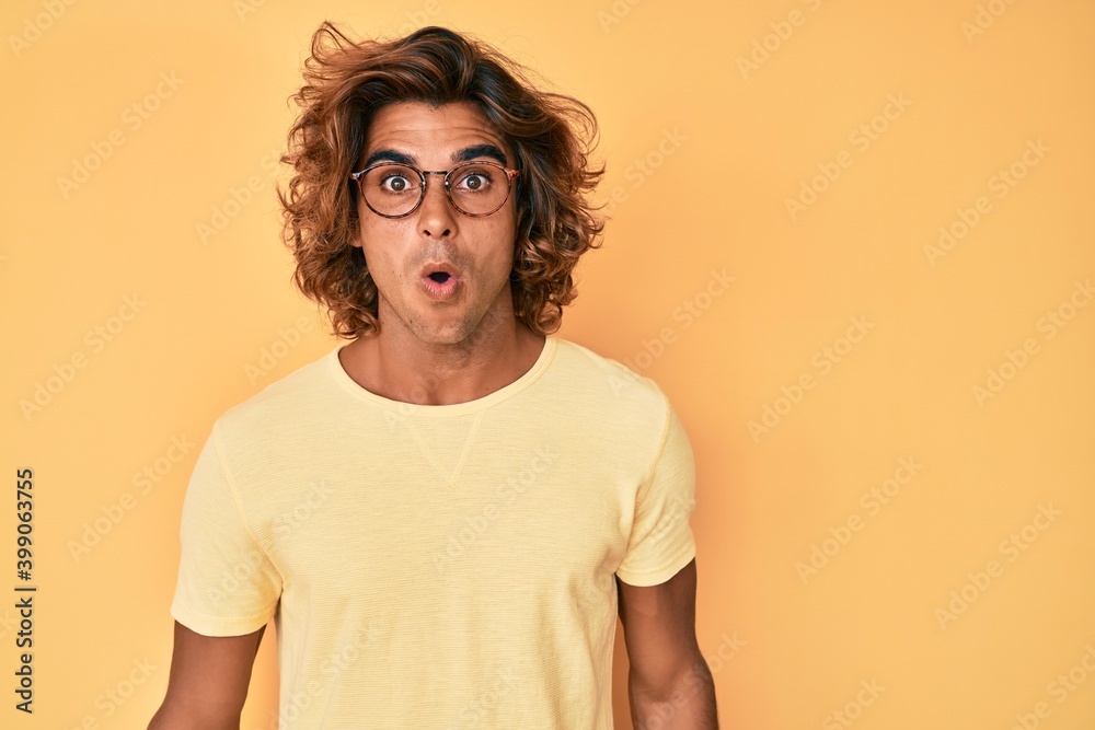 Young hispanic man wearing casual clothes and glasses scared and amazed with open mouth for surprise, disbelief face