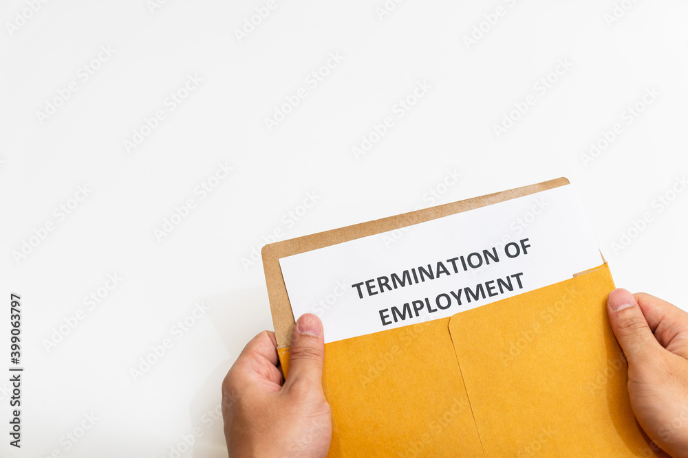 Termination of employment letter and its envelope are in the hands of a businessman. Termination of employment letter and its envelope are in the hands of a businessman.