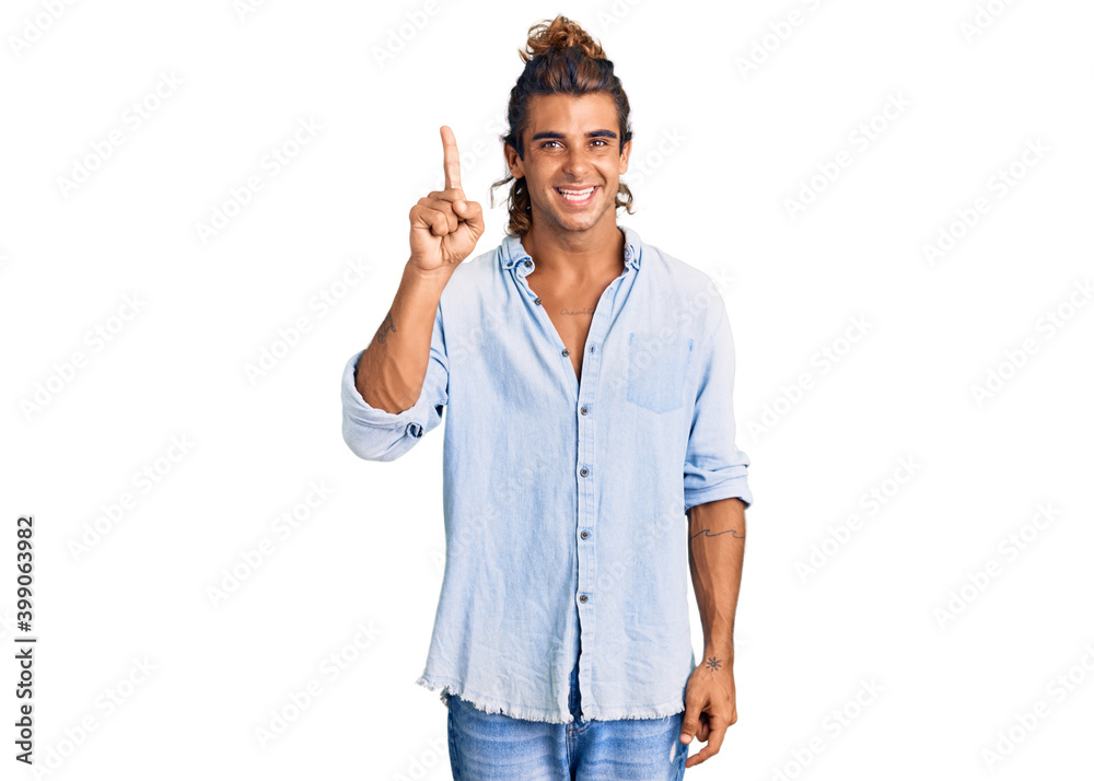 Young hispanic man wearing summer style pointing finger up with successful idea. exited and happy. number one. Young hispanic man wearing summer style pointing finger up with successful idea. exited and happy. number one.
