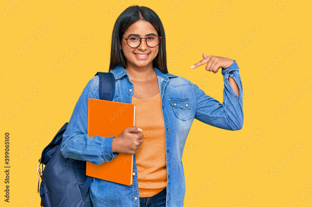 Young latin girl wearing student backpack and holding books looking confident with smile on face, pointing oneself with fingers proud and happy. Young latin girl wearing student backpack and holding books looking confident with smile on face, pointing oneself with fingers proud and happy.