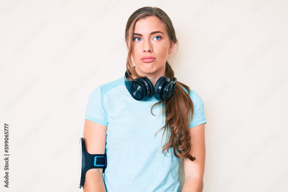 Beautiful young caucasian woman wearing gym clothes and using headphones depressed and worry for distress, crying angry and afraid. sad expression. Beautiful young caucasian woman wearing gym clothes and using headphones depressed and worry for distress, crying angry and afraid. sad expression.