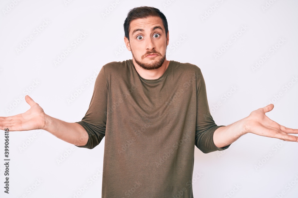 Young handsome man wearing casual clothes clueless and confused expression with arms and hands raised. doubt concept. Young handsome man wearing casual clothes clueless and confused expression with arms and hands raised. doubt concept.