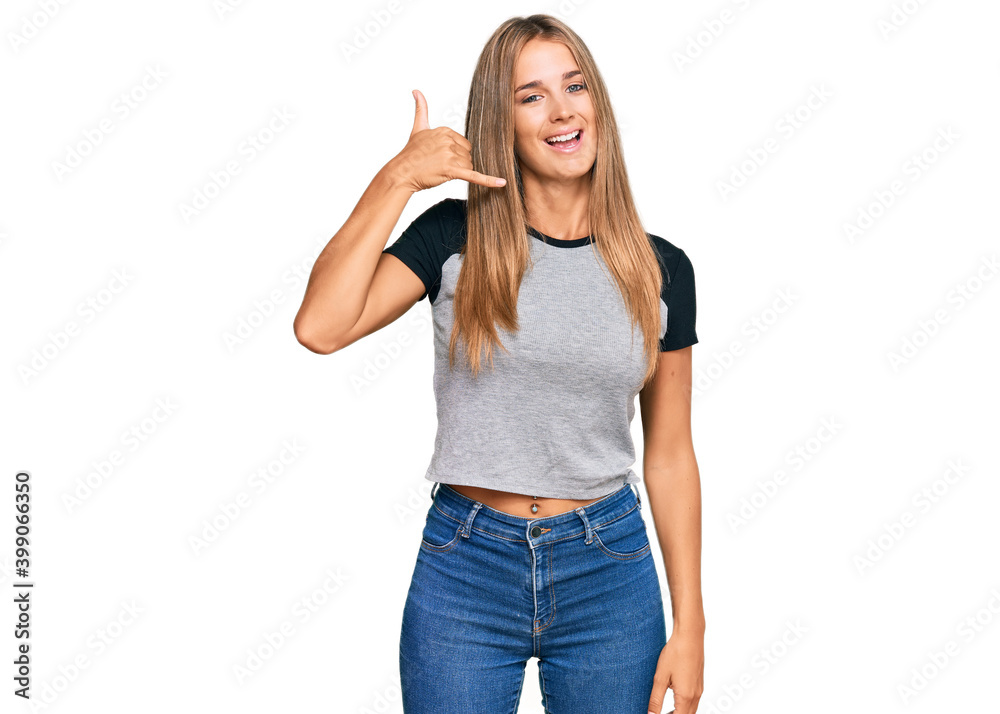 Young blonde woman wearing casual clothes smiling doing phone gesture with hand and fingers like talking on the telephone. communicating concepts. Young blonde woman wearing casual clothes smiling doing phone gesture with hand and fingers like talking on the telephone. communicating concepts.