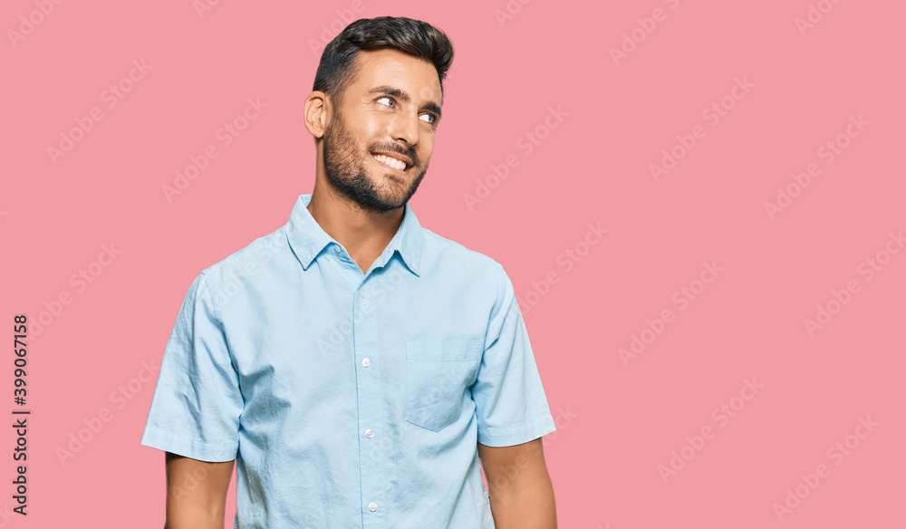Handsome hispanic man wearing casual clothes looking away to side with smile on face, natural expression. laughing confident.