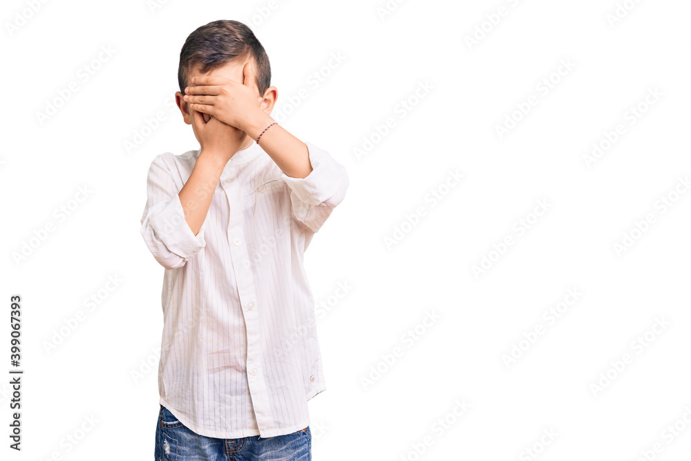 Cute blond kid wearing elegant shirt covering eyes and mouth with hands, surprised and shocked. hiding emotion Cute blond kid wearing elegant shirt covering eyes and mouth with hands, surprised and shocked. hiding emotion