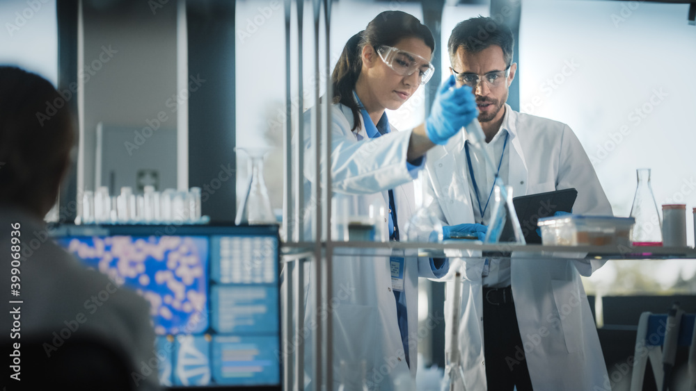Medical Science Laboratory with Diverse Team of Research Scientists Working. Microbiologist Working with Biochemists using Micropipette Dropper and Digital Tablet Computer. Medical Science Laboratory with Diverse Team of Research Scientists Working. Microbiologist Working with Biochemists using Micropipette Dropper and Digital Tablet Computer.