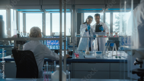 Medical Science Laboratory with Diverse Team of Biochemistry Research Scientists Talking, Two Microbiologists using Digital Tablet Computer, Micropipette. Developing Drugs, Gene Editing.