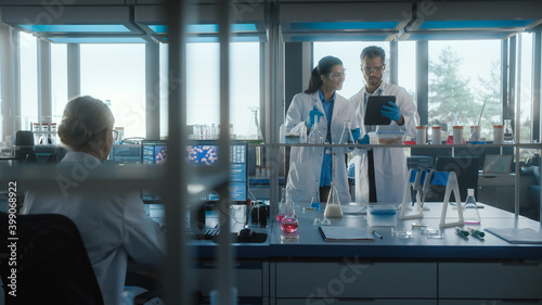 Medical Science Laboratory with Diverse Team of Biochemistry Research Scientists Talking  Two Microbiologists using Digital Tablet Computer  Micropipette. Developing Drugs  Gene Editing.