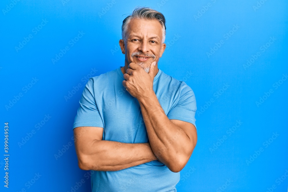 Middle age grey-haired man wearing casual clothes looking confident at the camera smiling with crossed arms and hand raised on chin. thinking positive. Middle age grey-haired man wearing casual clothes looking confident at the camera smiling with crossed arms and hand raised on chin. thinking positive.