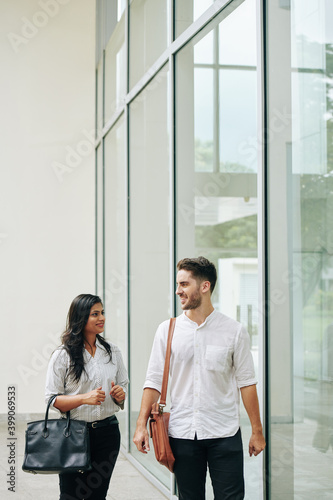Smiling young multi-ethnic business couple walking down street and discussing news Free Download Smiling young multi-ethnic business couple walking down street and discussing news - GFXLoad