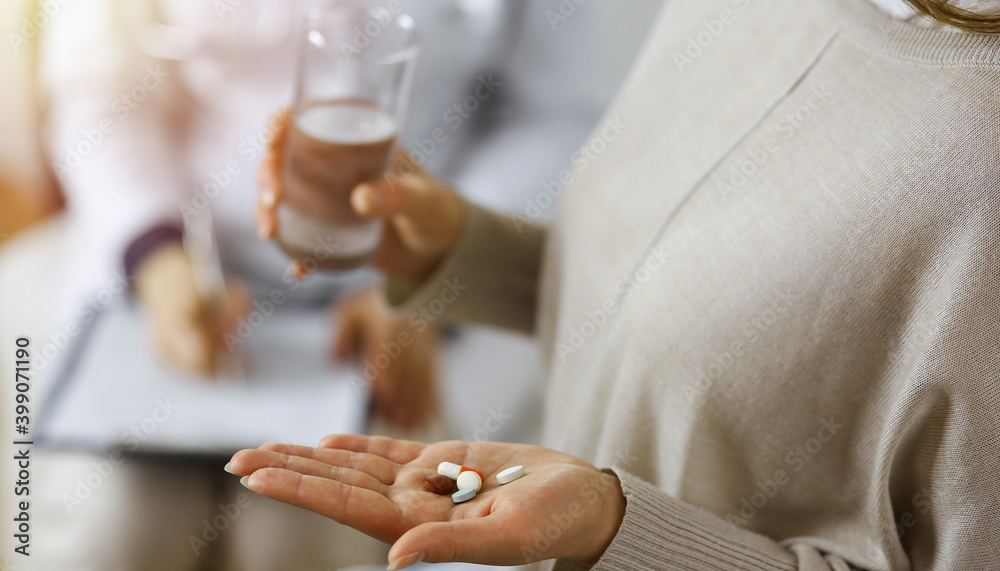 Obraz premium Close-up woman-patient holding pills near her doctor, time to take medications for headache. Stay at home concept during Coronavirus pandemic and self isolation quarantine. Covid 2019