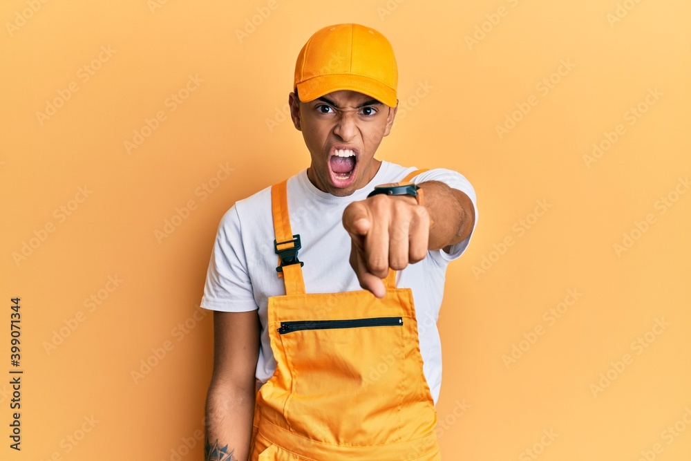 Young handsome african american man wearing handyman uniform over yellow background pointing displeased and frustrated to the camera, angry and furious with you