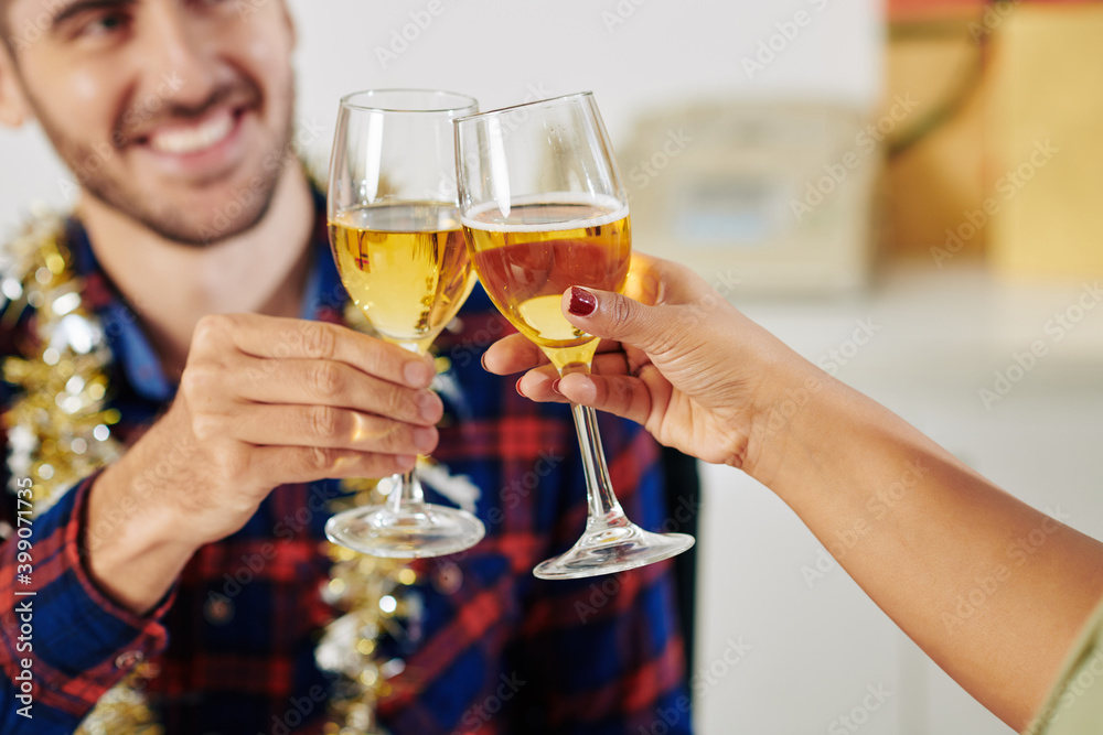 Close-up image of colleagues enjoying small Christmas celebration and toasting with chamagne glasses