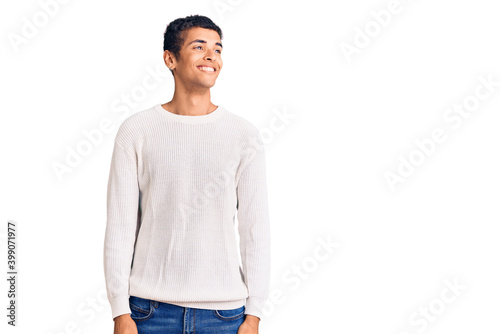 Young african amercian man wearing casual clothes looking away to side with smile on face, natural expression. laughing confident.