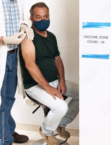 Male professional physician with sterile gloves who inject the vaccine to elderly men who wear a medical mask. Vaccination, medication, and health care. Covid vaccine, coronavirus.    photo