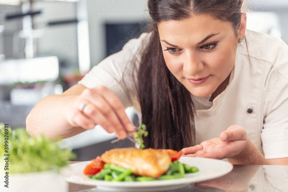 Plating of healthy food in a professional kitchen by a woman chef