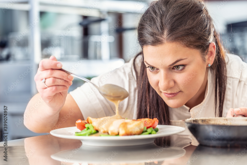 Female chef pours a mushroom sauce over meat with vegetables from a ladle in a pro kitchen Female chef pours a mushroom sauce over meat with vegetables from a ladle in a pro kitchen
