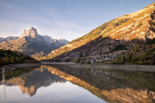 Mountain with water refllection in a lake with autumn tree forest and a small town in Aragon, Heusca, Spain © LeeSensei