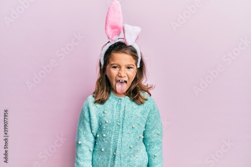 Φωτογραφία Little beautiful girl wearing cute easter bunny ears sticking tongue out happy with funny expression