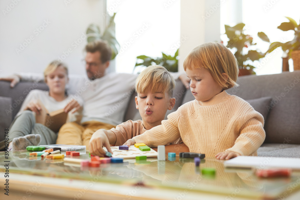 Portrait of cute blonde boy playing with little sister while enjoying time with family at home, copy space Portrait of cute blonde boy playing with little sister while enjoying time with family at home, copy space
