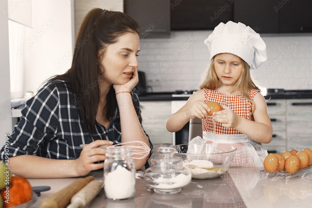 Family in a kitchen. Beautiful mother with little daughter. Woman in a black shirt. Family in a kitchen. Beautiful mother with little daughter. Woman in a black shirt.