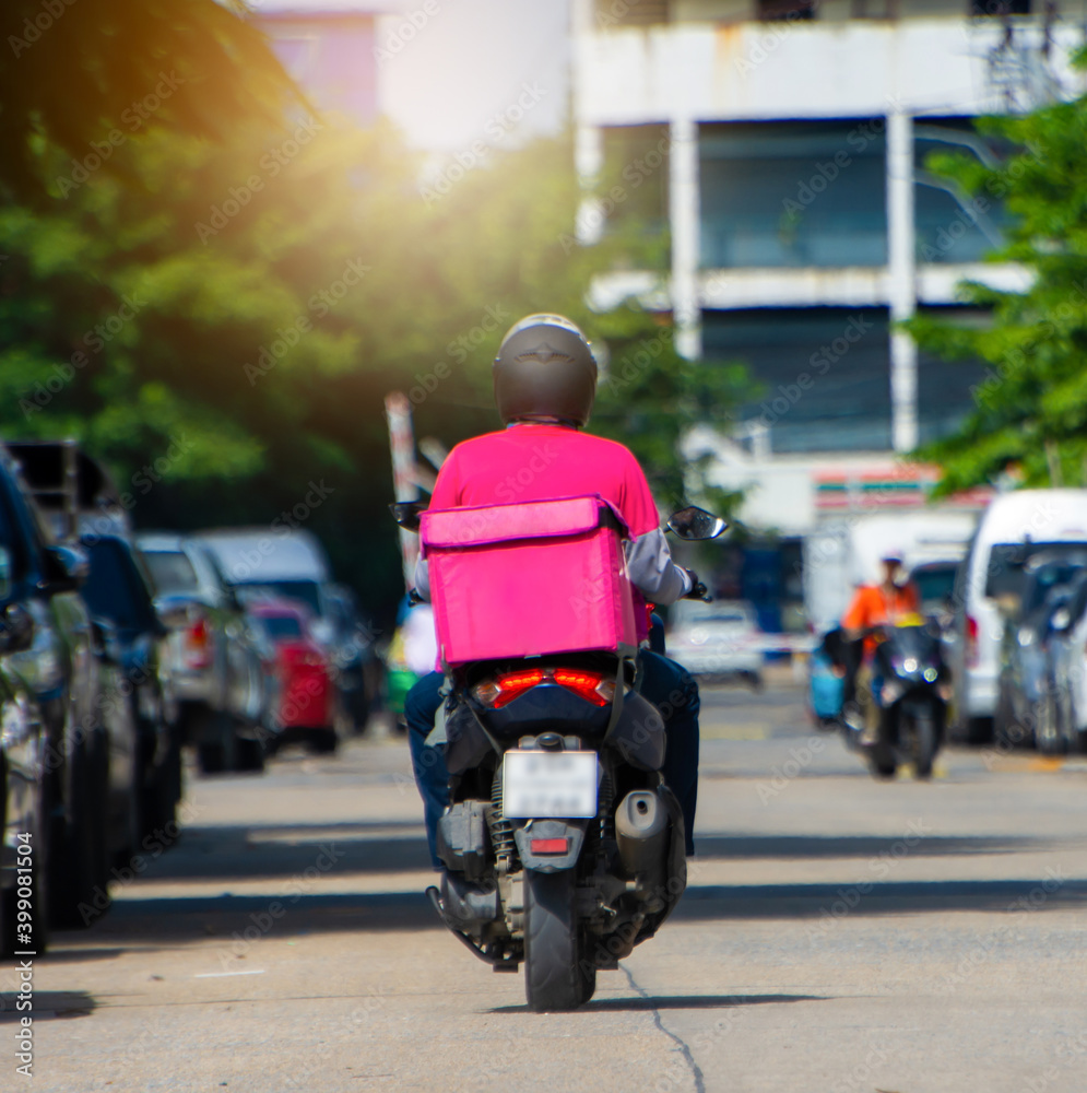 The back of a motorcyclist delivers food in a pink dress form, a pink food bag is rushing to deliver to customers online.