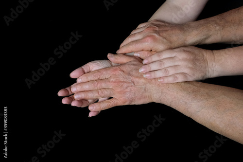 male and female hands together on black background, old skin with wrinkles and veins, concept of health, love, concept of caring, supporting each other