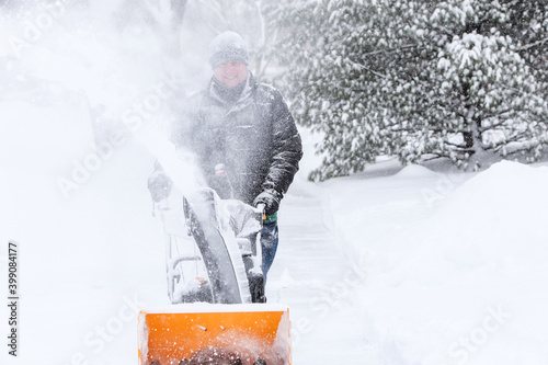Man using a snowblower to clear his sidewalk and driveway photo