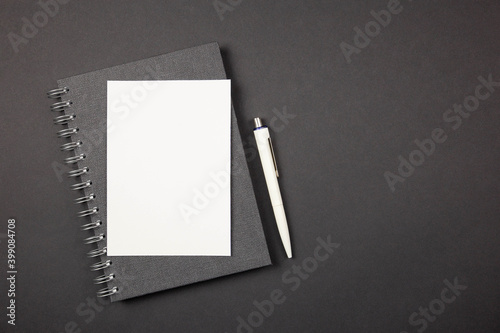 Blank greeting card with pen. Stationery desktop mockup scene. Dark table background. Flat lay. Top view. Copy space.