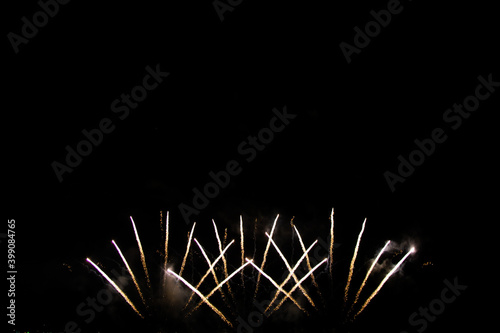 Beautiful multi color fireworks explosions lighting sky over trees silhouette and over an illuminated,colorful fireworks celebration concept