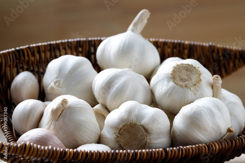 Garlic Cloves and Bulb in vintage organic woven wooden basket on dark black background. spice is an herb that is grown around the world.