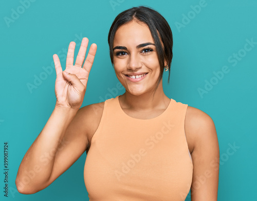 Young brunette woman wearing casual clothes showing and pointing up with fingers number four while smiling confident and happy.