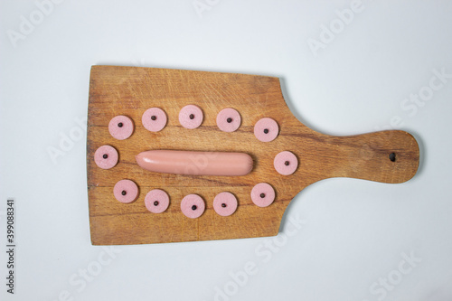 Sausages on a wooden board. Sliced sausage around a whole sausage. meat product on a white background.