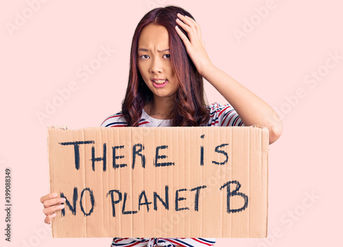 Young beautiful chinese girl holding there is no planet b banner stressed and frustrated with hand on head, surprised and angry face © Krakenimages.com