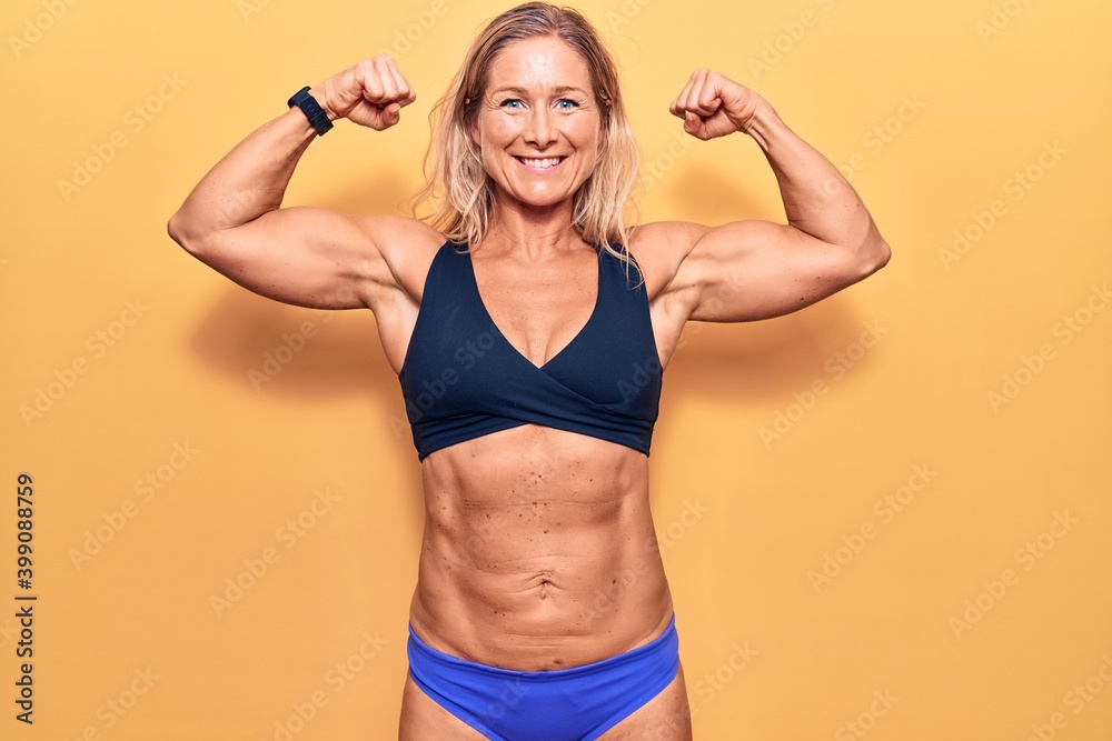 Young blonde sportswoman posing showing arm muscle and abs Young blonde sportswoman posing showing arm muscle and abs