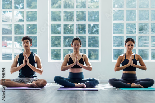 Group of young sporty attractive people practicing yoga lesson with instructor. Instructor woman leading exercise pose, Healthy lifestyle, working out, indoor full length, studio background.