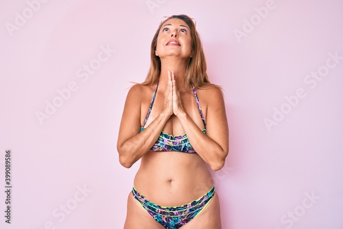 Middle age hispanic woman wearing bikini begging and praying with hands together with hope expression on face very emotional and worried. begging.
