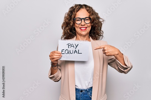 Bilde på lerret Middle age beautiful woman holding paper with pay equal message over white backg