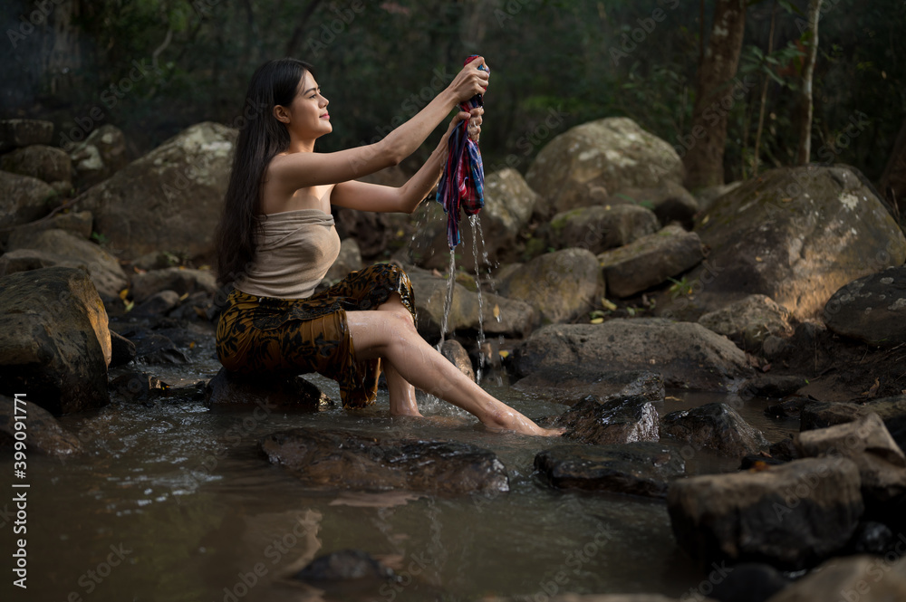 Portrait Asian young woman washing clothes at the stream.Beautiful Village women sitting and washing the clothes at the river.Countryside life style concept. Portrait Asian young woman washing clothes at the stream.Beautiful Village women sitting and washing the clothes at the river.Countryside life style concept.