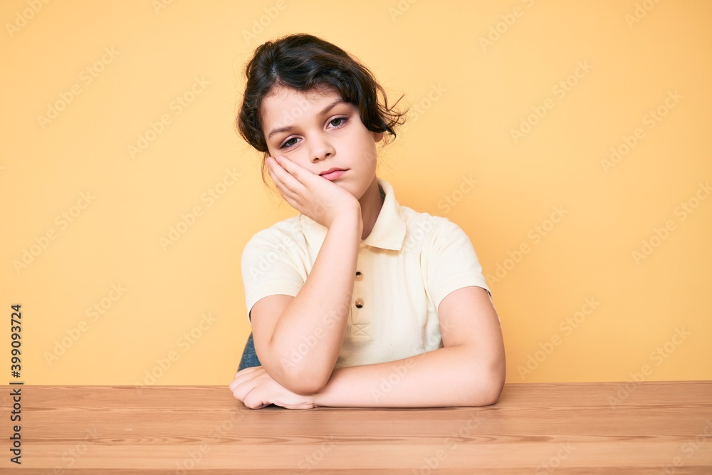 Cute hispanic child wearing casual clothes sitting on the table thinking looking tired and bored with depression problems with crossed arms. Cute hispanic child wearing casual clothes sitting on the table thinking looking tired and bored with depression problems with crossed arms.