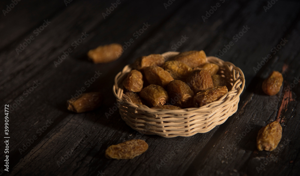 Dried dates in basket on a dark wooden background