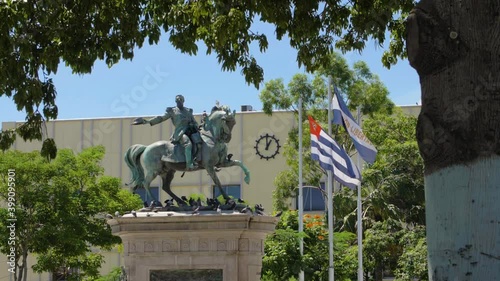 A daytime view of the statue of Capitain Gerardo Barrios in the heart of the historic district of San Salvador, El Salvador next to the country's and city's waving flag. photo