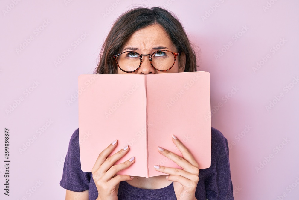 Young beautiful woman wearing glasses reading book angry and mad screaming frustrated and furious, shouting with anger looking up. - obrazy, fototapety, plakaty 