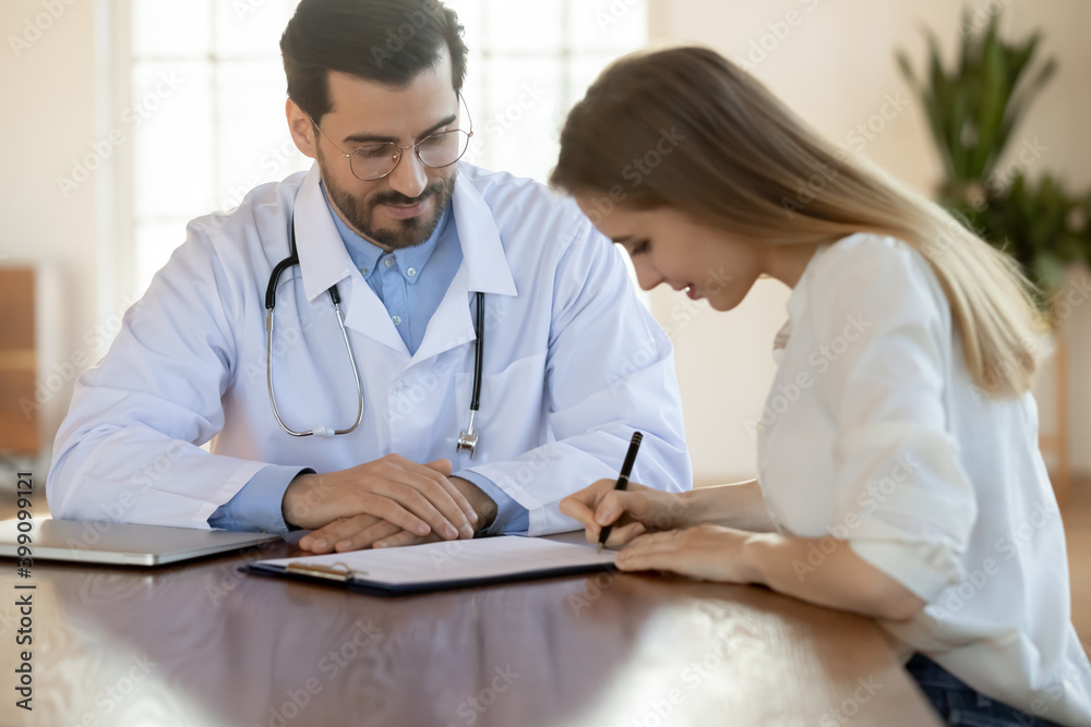 Female patient put signature on paperwork close deal with male GP or physician in private hospital. Woman client sign paper document mage health insurance agreement with man doctor in clinic. Female patient put signature on paperwork close deal with male GP or physician in private hospital. Woman client sign paper document mage health insurance agreement with man doctor in clinic.