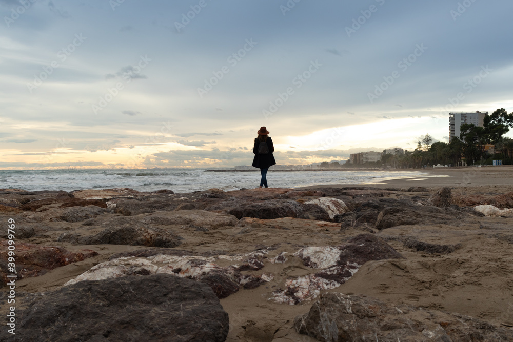 Woman enjoying the sunset walking along the beautiful benicassim beaches in Castellon bathed by the Mediterranean Sea in Spain