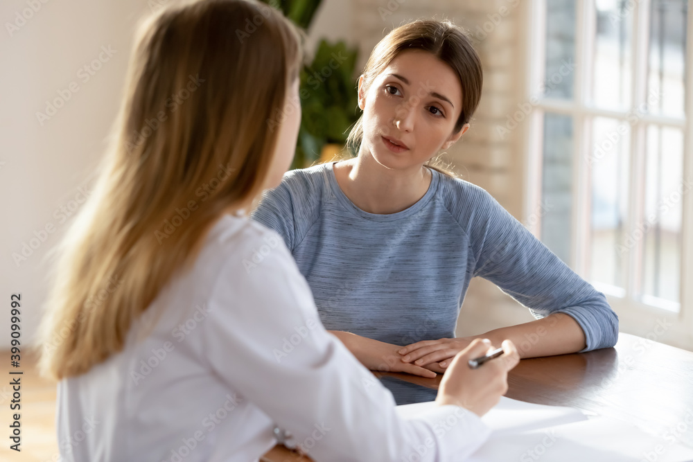 Φωτογραφία Young Caucasian female patient talk with nurse or GP at consultation in private hospital