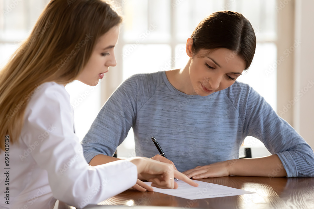 Young Caucasian female patient put signature on paperwork make agreement with GP doctor in private clinic. Woman client sign paper document close deal with physician in hospital. Healthcare concept. Young Caucasian female patient put signature on paperwork make agreement with GP doctor in private clinic. Woman client sign paper document close deal with physician in hospital. Healthcare concept.
